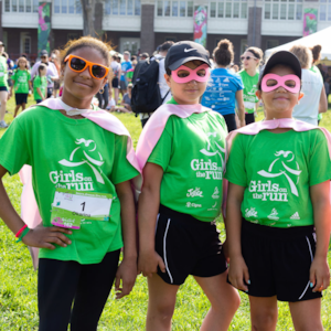 Girls on the Run participants stand in superhero gear at the 5K, looking strong and happy